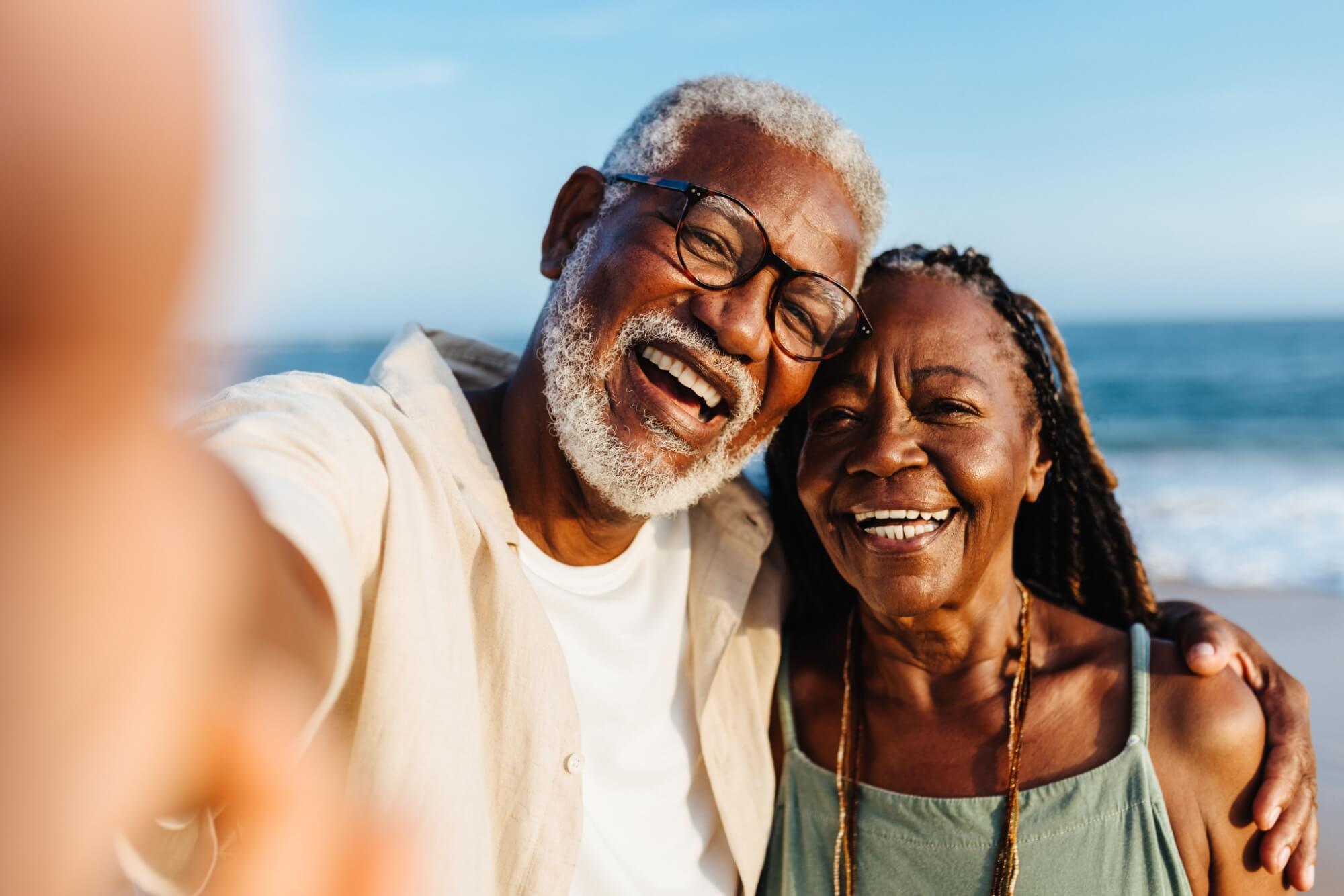 older couple shares a joyful moment while taking a selfie on a sunny seaside
