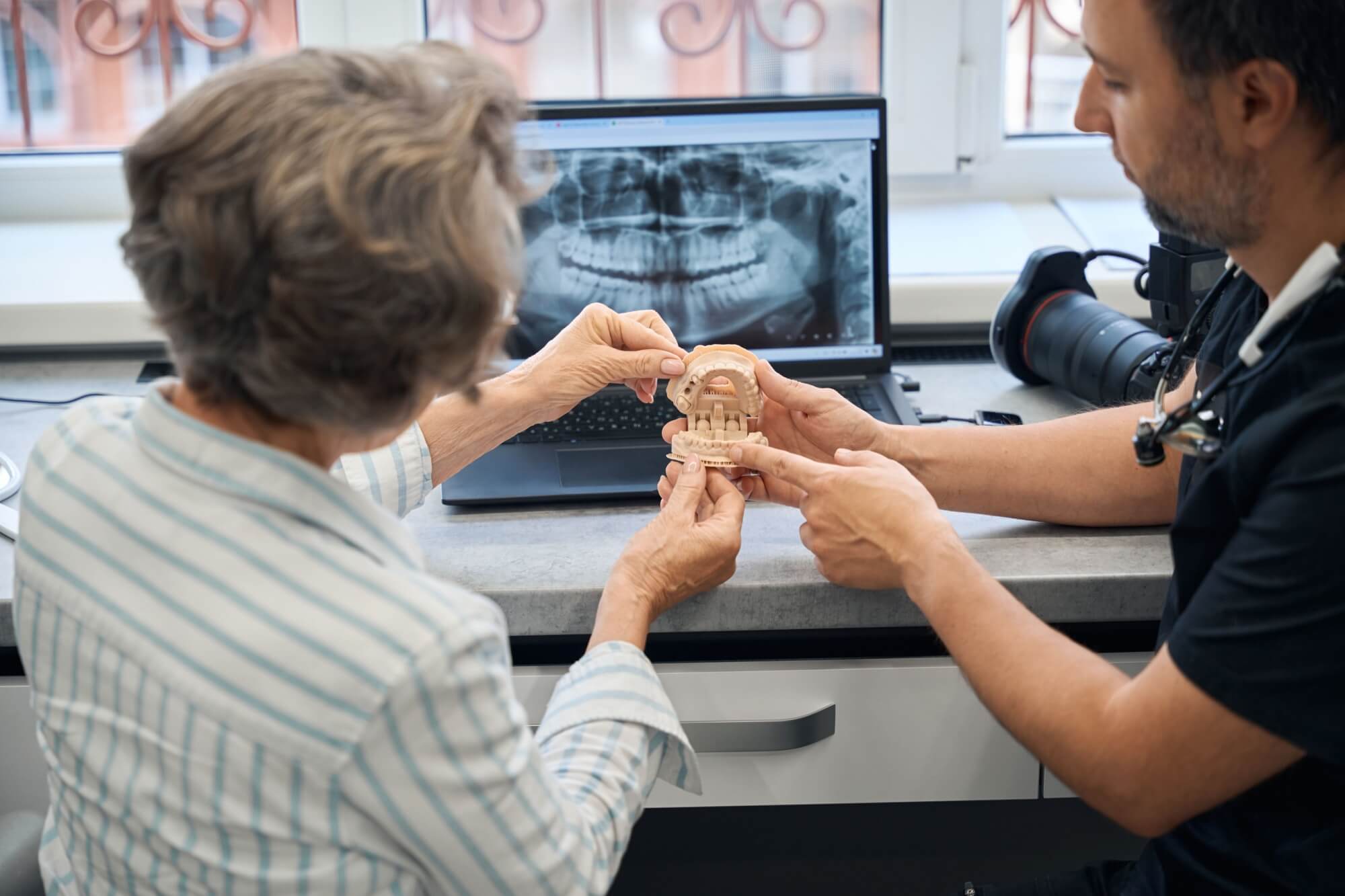 Male dental technician is consulting an elderly lady