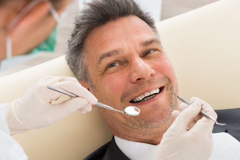 Happy Mature Man Having Dental Check-up In Clinic