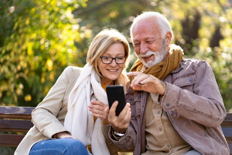 Cheerful elderly couple sitting on a bench in the public park