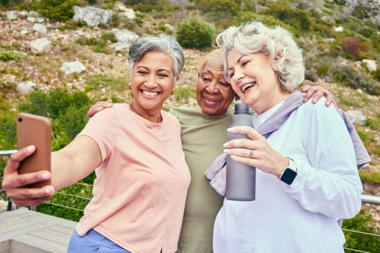 happy elderly friends hiking and taking selfie